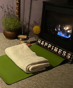 A yoga mat in front of a fireplace with a "happiness" sign on the mat.